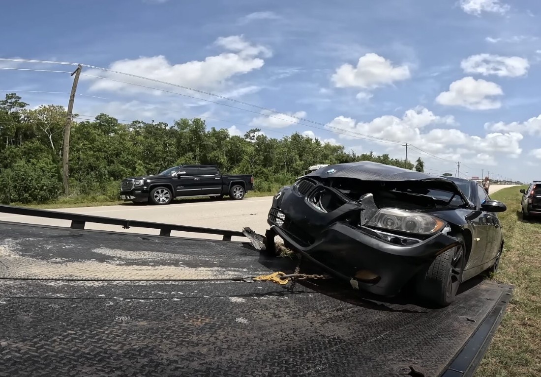 Accident recovery service with damaged vehicle on flatbed truck